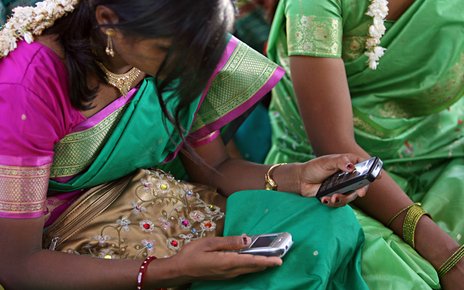 A young woman uses mobile phones during a community meeting in Aurangabad..jpg